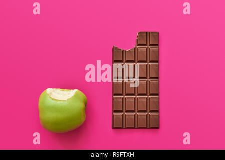 Dieta o un buon concetto di salute. Possibilità di scelta tra cibi sani come fresh apple o dolci dolci al cioccolato Foto Stock