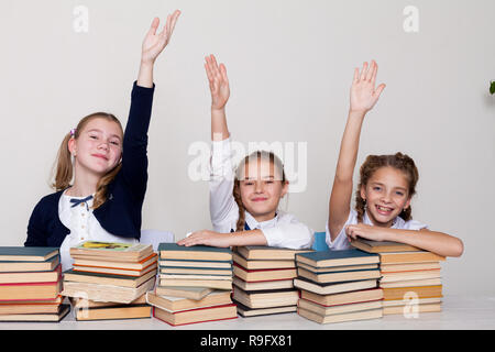 Tre ragazze in aula, ha sollevato una mano fino a rispondere Foto Stock