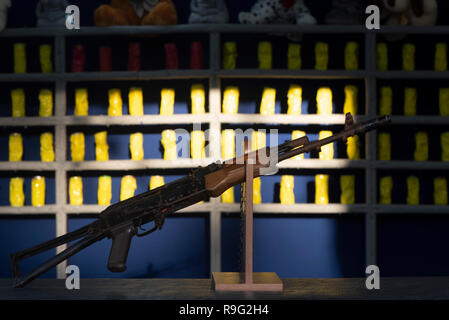 Galleria di tiro, pistola ad aria in primo piano. in background, le banche sono intaccati dagli scatti. sulla parte superiore dei giocattoli come premi. Foto Stock