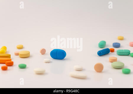 Farmaci in forma di medicinali. Capsule e compresse di varie forme e colori per uso umano. I prodotti farmaceutici su sfondo bianco. Foto Stock