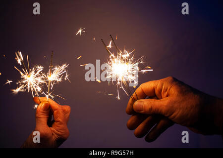 Le mani della coppia di anziani azienda brilla per celebrare il nuovo anno Foto Stock