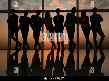 Silhouette di un team aziendale in piedi accanto alla finestra di ufficio Foto Stock