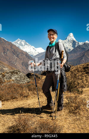 Il Nepal, il Campo Base Everest Trek, senior trekker femmina con pali trekking tra le montagne himalayane Foto Stock