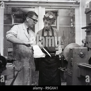 1968, a sud di Londra boys Boarding School, in una lamiera di classe, un insegnante maschio aiutare un alunno utilizzare macchinari e strumenti , Inghilterra, Regno Unito. Foto Stock