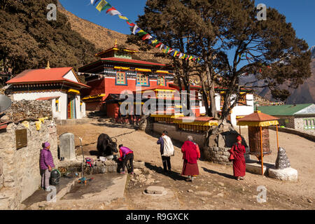 Il Nepal, il Campo Base Everest Trek, Khumjung, monaci passando tradizionali ruote di preghiera e mani pietre fuori dal villaggio gompa Foto Stock