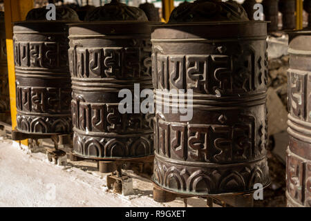 Il Nepal, il Campo Base Everest Trek, Khumjung, ottone tradizionali ruote della preghiera nel villaggio di parete chorten Foto Stock