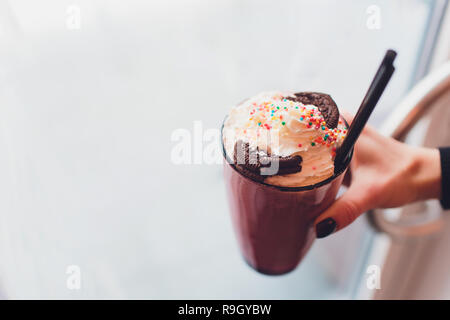 Ragazza con frullato con ciambelle e altri dolci in vaso Foto Stock