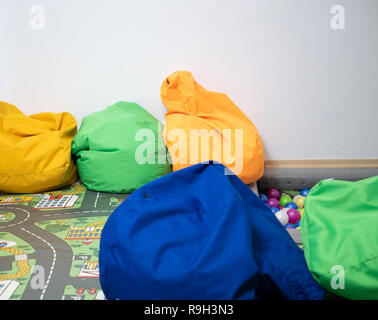 Sacco di vivida vibrante sacchi di fagioli al parco giochi per bambini zona al kindergarten, immagine interna con un sacco di spazio copia su sfondo bianco parete Foto Stock