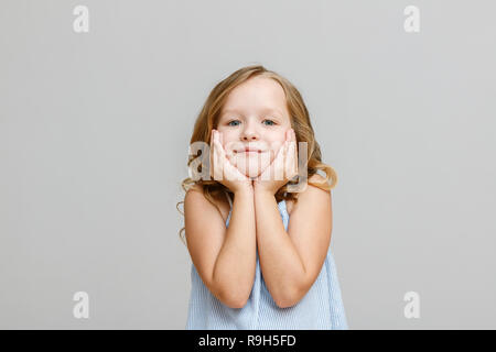 Ritratto di un grazioso piccolo bambino biondo girl su uno sfondo grigio Foto Stock