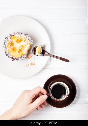 Donna di bere il caffè e mangiare la torta su bianco tavolo in legno Foto Stock