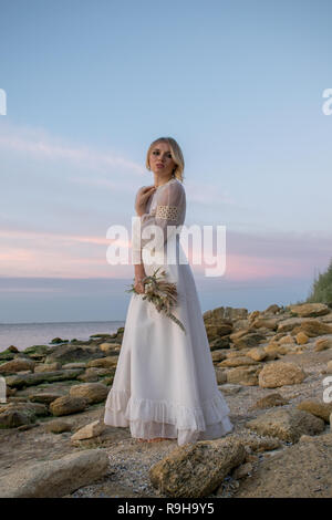 Elegante giovane donna in bianco abiti lunghi su sfondo del mare Foto Stock