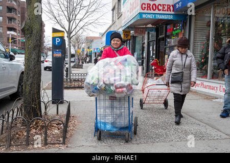 Una donna di mezza età raccogliendo lattine vuote per deposito. Sulla 37th Avenue a Jackson Heights, Queens, a New York City. Foto Stock