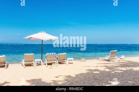 Sedie a sdraio su una bella spiaggia tropicale in una giornata di sole. Foto Stock