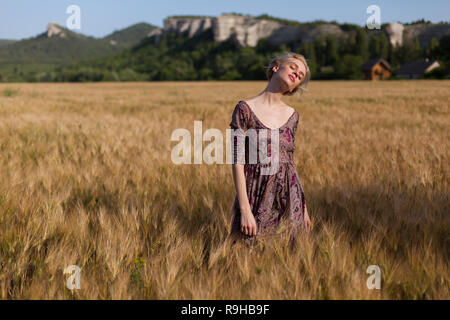 Una contadina in un campo di grano maturo harvest Foto Stock