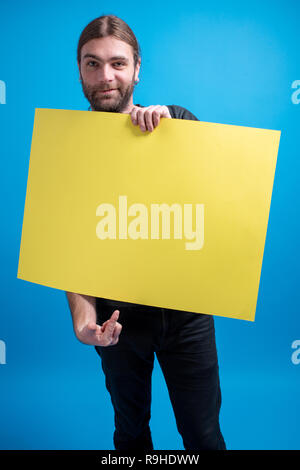 Ritratto di uomo in possesso di un banner giallo billboard. Copia dello spazio disponibile per il contenuto pubblicitario Foto Stock