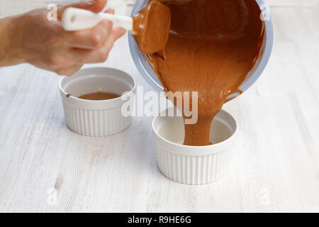 Impasto crudo viene versata in uno stampo in ceramica per la cottura di cioccolato dessert di mandorla Foto Stock