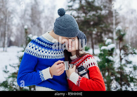 Coppia giovane bere il tè e abbracciando nella foresta d'inverno. Le persone felici di relax all'aperto durante i giorni festivi. Il giorno di San Valentino Foto Stock