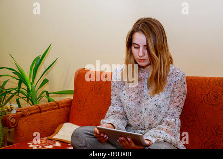 Immagine ritagliata della ragazza giovane con tavoletta digitale in camera Foto Stock