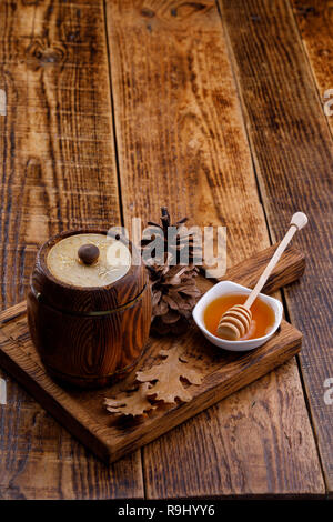 Barile di legno con miele e stick cucchiaio su un bordo decorativo. Lo spazio al di sotto del testo. Close-up. Foto Stock