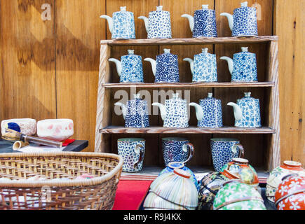 Giapponese in stile asiatico di porcellana per la vendita nel negozio di ceramiche a Kyoto, in Giappone. Decorate teiere, tazze e scodelle fatti a mano su supporti in legno Foto Stock