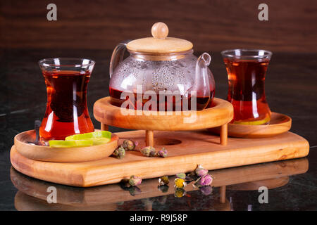 Tradizionale tè turco cup, la cerimonia del tè, la tazza di appena infuso di tè nero, calda luce morbida, più scuro dello sfondo in marmo Foto Stock