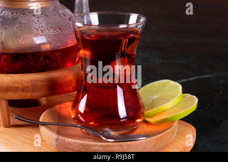 Tradizionale tè turco cup, la cerimonia del tè, la tazza di appena infuso di tè nero, calda luce morbida, più scuro dello sfondo in marmo Foto Stock