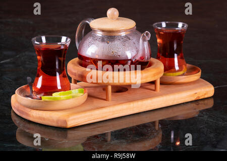 Tradizionale tè turco cup, la cerimonia del tè, la tazza di appena infuso di tè nero, calda luce morbida, più scuro dello sfondo in marmo Foto Stock
