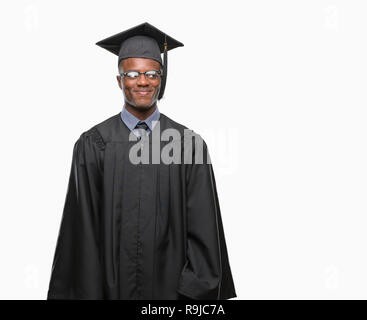 Giovane laureato americano africano uomo su sfondo isolato sorridente cercando lato e lo sguardo lontano pensando. Foto Stock