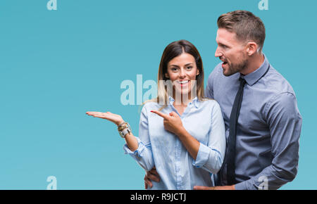 I giovani lavoratori azienda giovane su sfondo isolato stupiti e sorridente alla fotocamera durante la presentazione con la mano e puntando con il dito. Foto Stock