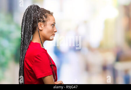 Giovani capelli intrecciati African American Girl su sfondo isolato guardando al lato, profilo relax posano con faccia naturale con sorriso sicuro. Foto Stock