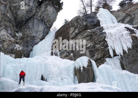 Maschio ice climber rappelling off una ripida cascata ghiacciata in inverno Foto Stock