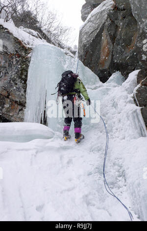 Maschio ice climber rappelling off una ripida cascata ghiacciata in inverno Foto Stock