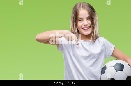 Giovane bella ragazza con soccer football palla su sfondo isolato con sorpresa faccia puntare il dito a se stesso Foto Stock