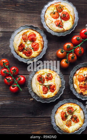 Fresche crostate con pomodorini e formaggio di capra su legno rustico sfondo. Vista dall'alto. Foto Stock