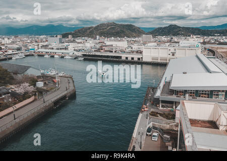 Angolo di alta vista del porto di Numazu Mercato del Pesce distretto con città di Numazu in background su un giorno nuvoloso Foto Stock