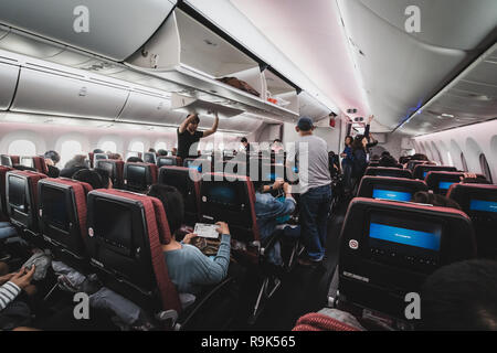 Chiba, Giappone - 16 Aprile 2017: all'interno della cabina della Japan Airlines Boeing 787-900. Il passeggero sono memorizzare i loro bagagli e appartenenti prima del decollo Foto Stock