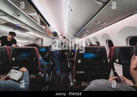 Chiba, Giappone - 16 Aprile 2017: all'interno della cabina della Japan Airlines Boeing 787-900. Il passeggero sono memorizzare i loro bagagli e appartenenti prima del decollo Foto Stock