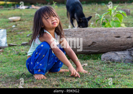 Thakhek, Laos - 19 Aprile 2018: ragazza locale in posa circondato da erba in una zona remota del Laos Foto Stock