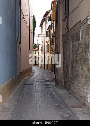 Avvolgimento tipico toscano strette strade lastricate in ombra con la pianura parete blu e muratura in pietra, pluviali e finestre con persiane in Pisa, Italia Foto Stock