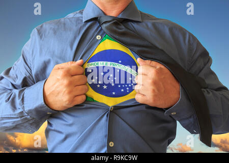 Business man tirando la sua t-shirt aperto e mostra il Brasile bandiera nazionale. Cielo blu con nuvole in background. Foto Stock
