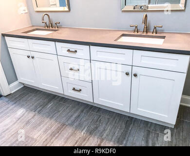 Moderno bagno interno design degli shaker mobili bianchi, piano in granito, due lavandini bianchi e pavimenti in porcellana piastrelle Foto Stock