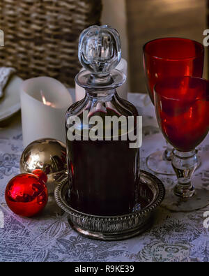 Crystal decanter. Isolato. Festosa decanter di cristallo riempita con il vino rosso. Rosso due bicchieri di cristallo sulla tavola con candela e deco . Immagine di stock Foto Stock