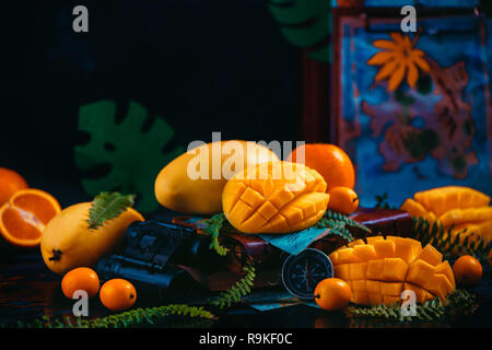 Mango, arance, kumquat e altri frutti tropicali su sfondo scuro con copia spazio. In viaggio per la scoperta di frutti esotici concetto. Foto Stock