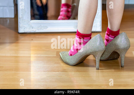 Bambina indossa grande tacco alto madre di scarpe. Foto Stock