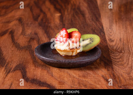 Frutta e bacche dessert crostata con kiwi e fragola su sfondo di legno. Fresh deliziosa torta dolce con fragole, kiwi e crema. Foto Stock