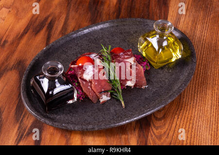 La salsa di soia e olio di oliva a crudo con bagno turco fette di bacon su sfondo di legno Foto Stock