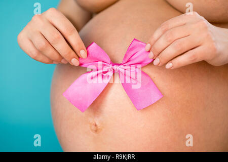 Donna incinta con un fiocco rosa sul suo ventre azienda scarpe per bambini  in mano Foto stock - Alamy