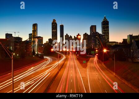 Atlanta Downtown skyline accesa fino al tramonto lungo la trafficata autostrada nelle ore di punta, ad Atlanta, Georgia, Stati Uniti d'America Foto Stock