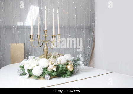 Nuovo Anno di decorazioni e un candelabro d'oro con candele accese in piedi sulla superficie di un pianoforte a coda Foto Stock