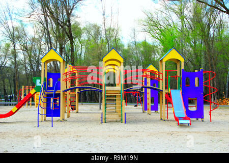 Parco giochi infantile nel parco della città. Swing giostra nel parco per bambini. Parco giochi per bambini luminoso multicolore. Moderna parco giochi per i bambini in città p Foto Stock